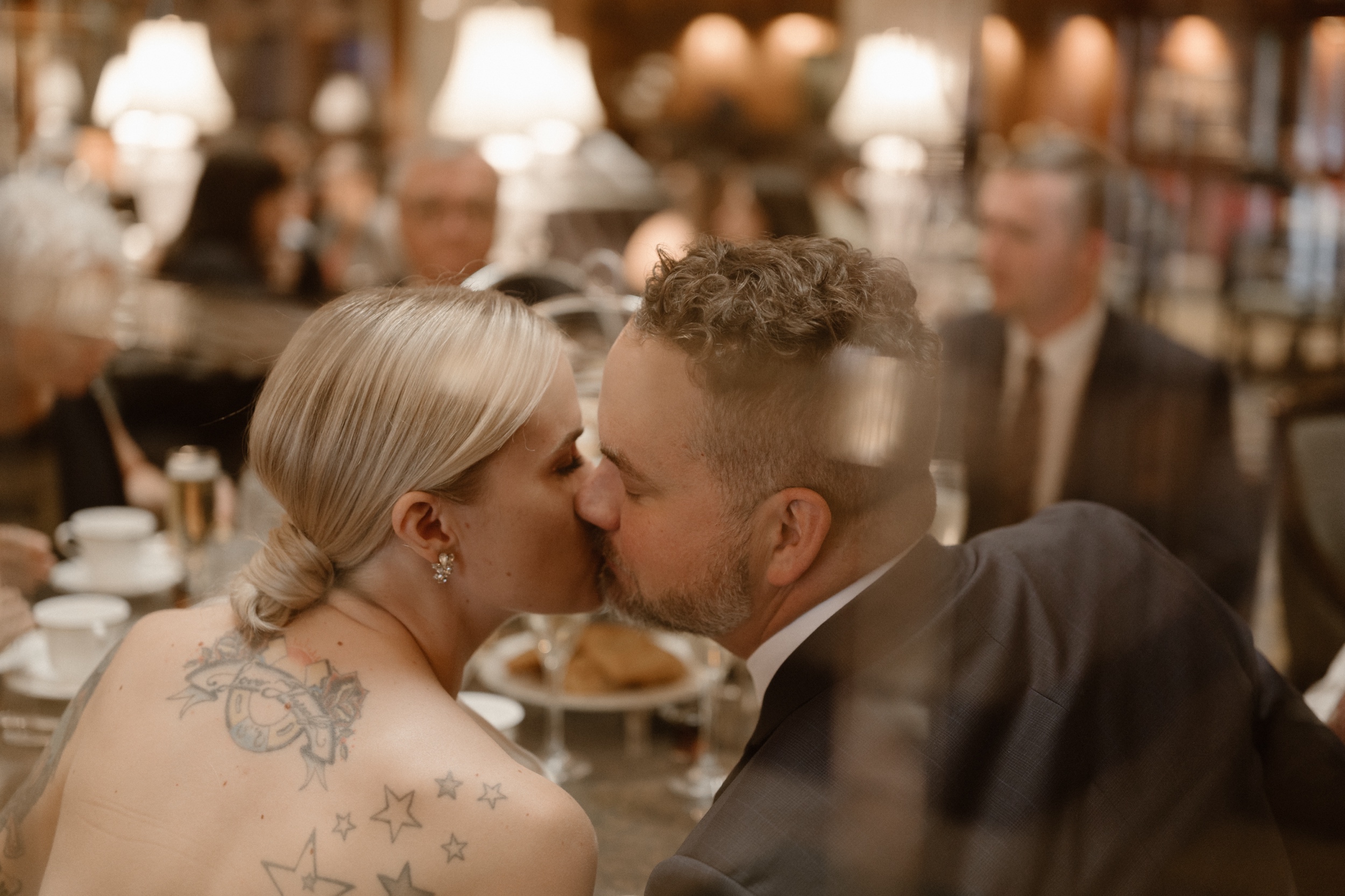 A bride and groom kiss one another at their high tea reception at the Brown Palace in Denver, Colorado. Photo by Denver wedding photographer Ashley Joyce.