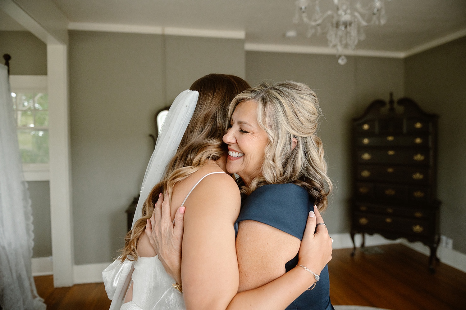 A bride and her mom hugging and smiling together