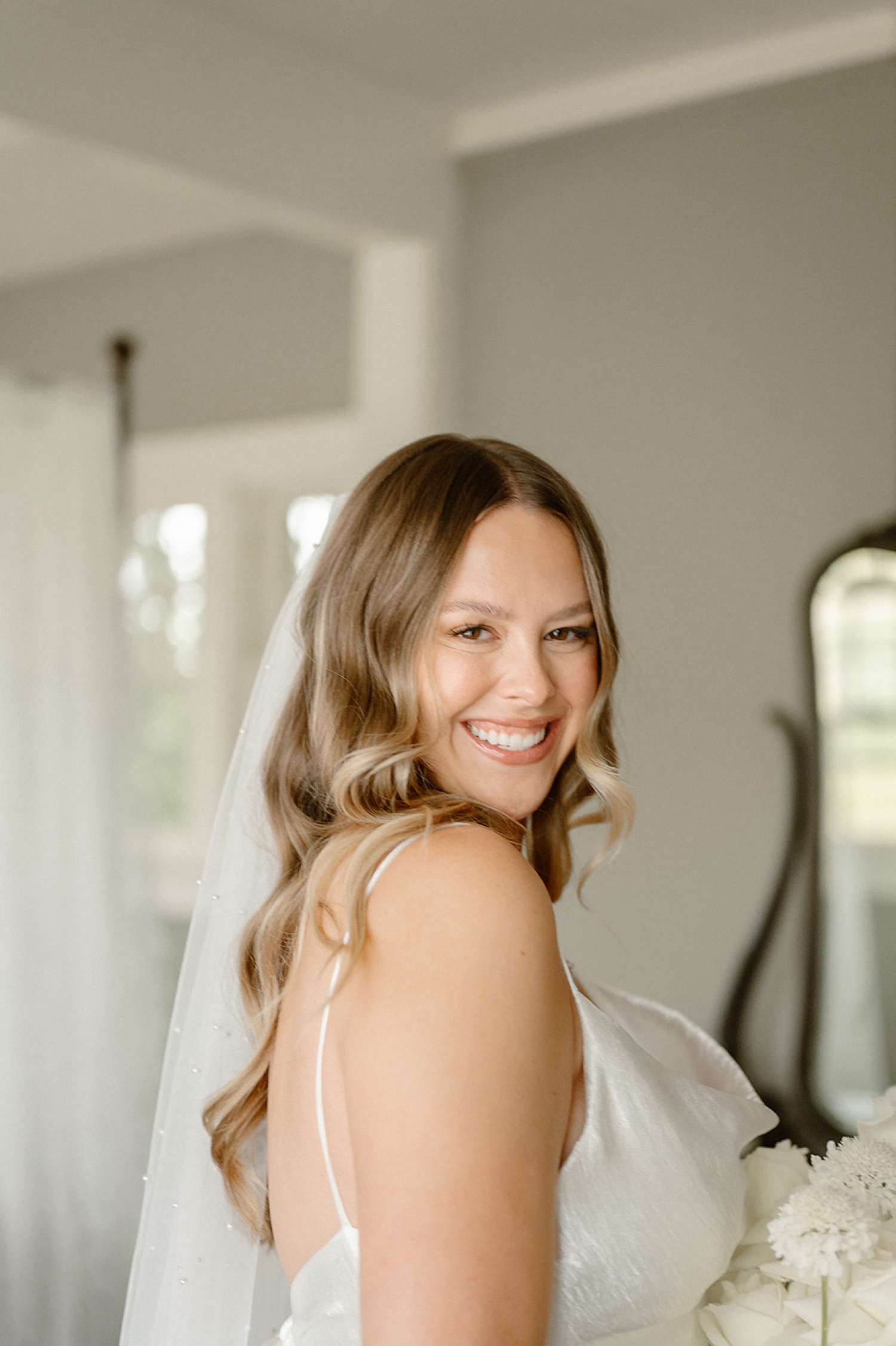 A bride looking over her shoulder and smiling at the camera