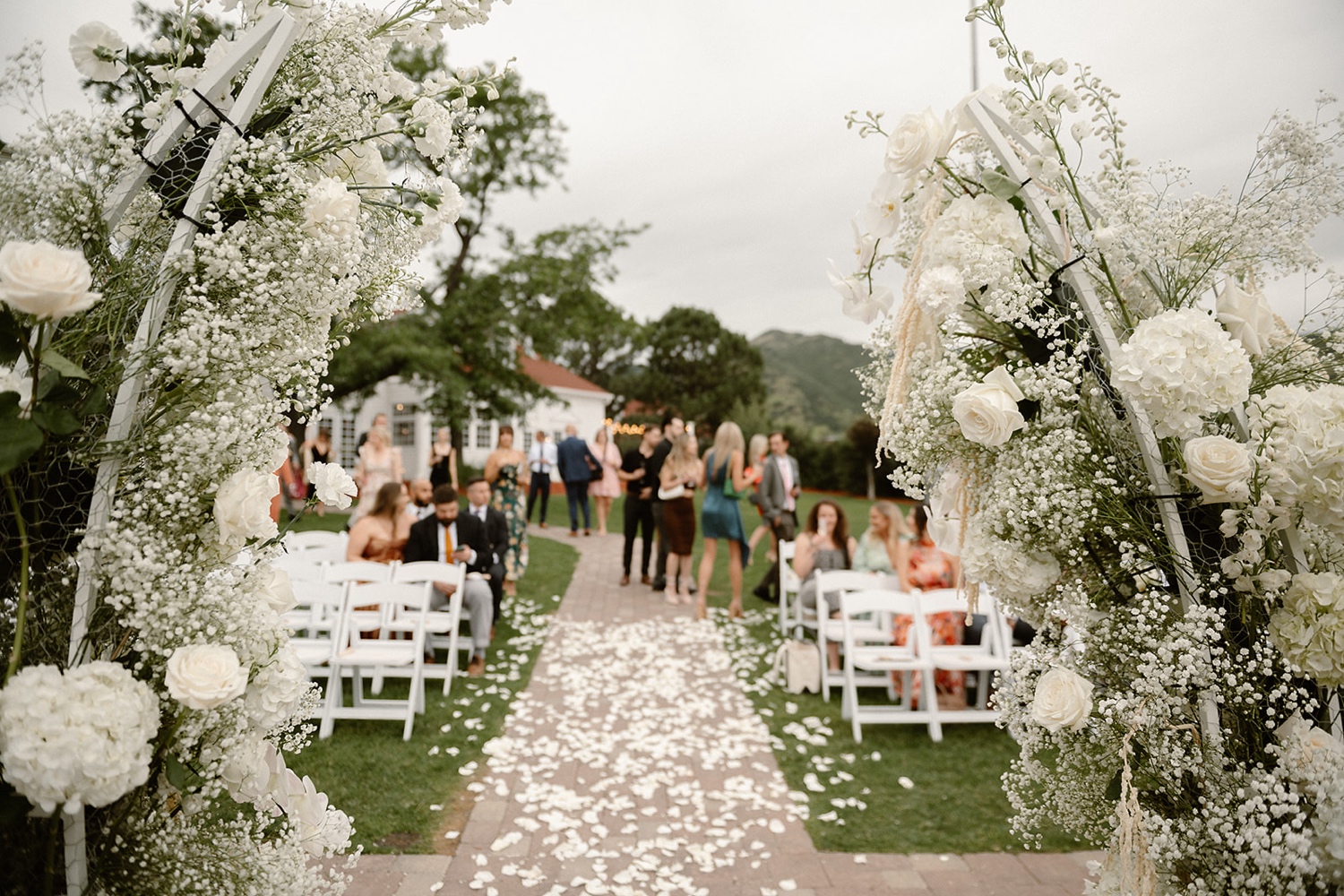 A wedding ceremony site with guests blurry in the background and a wedding arch in focus in the foreground