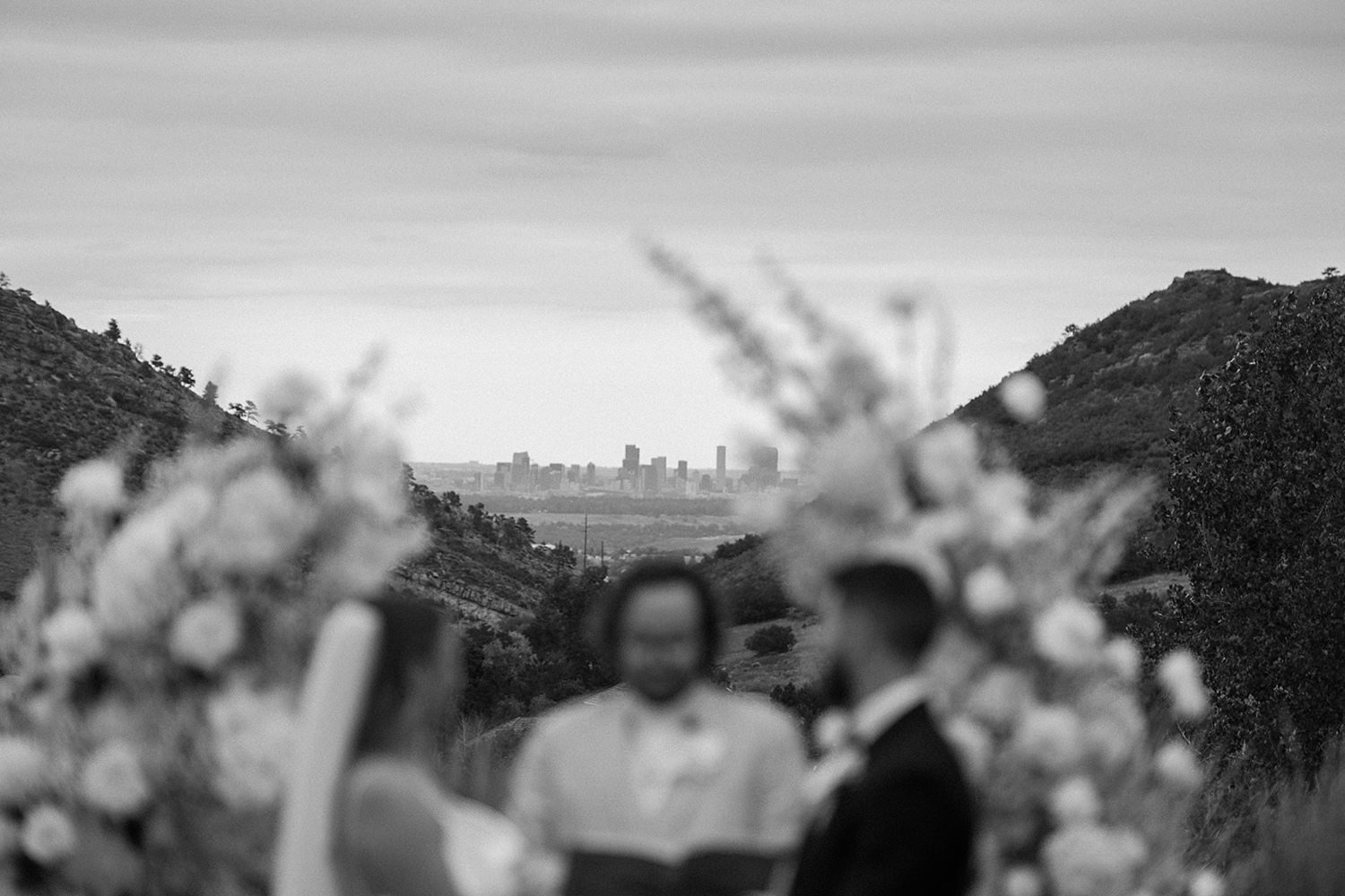 A photo of the Denver city skyline with the wedding couple standing for their ceremony in the foreground