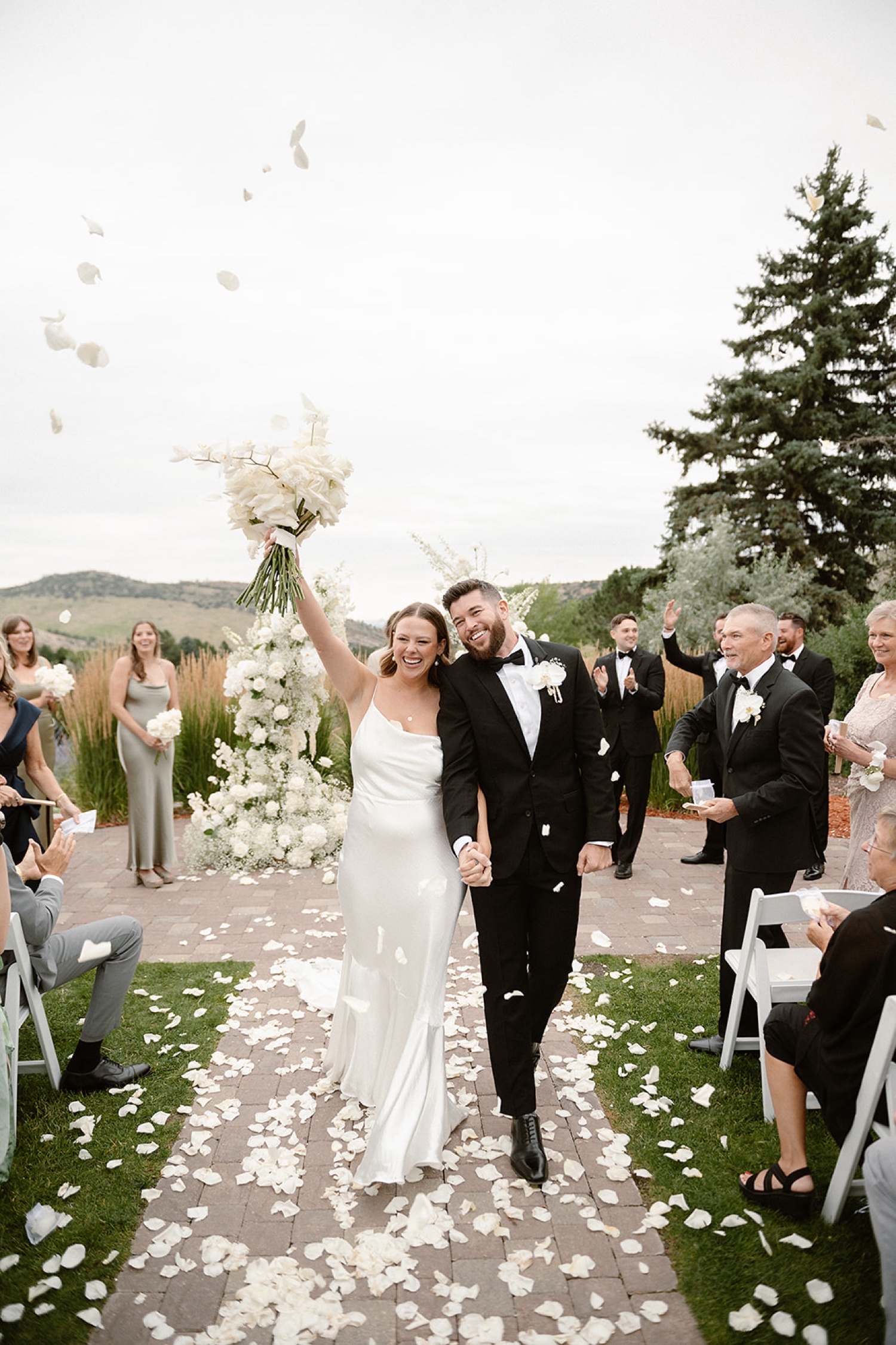 A bride and groom cheers the crowd while they walk down the aisle