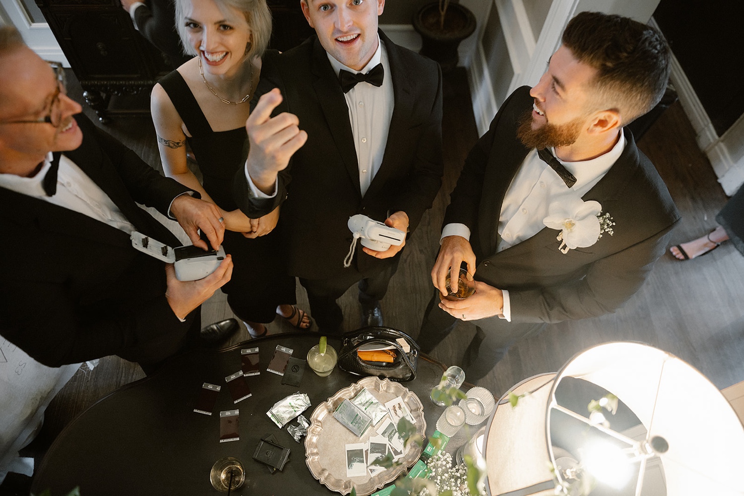 Wedding guests talk and laugh together while taking photos with a polaroid camera