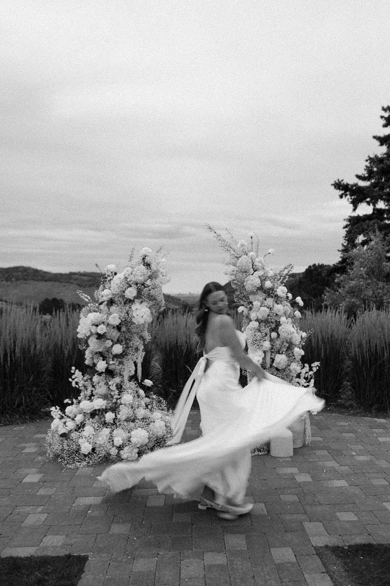 A blurry photo of a bride twirling in front of her wedding arch at The Manor House wedding venue in Littleton, Colorado