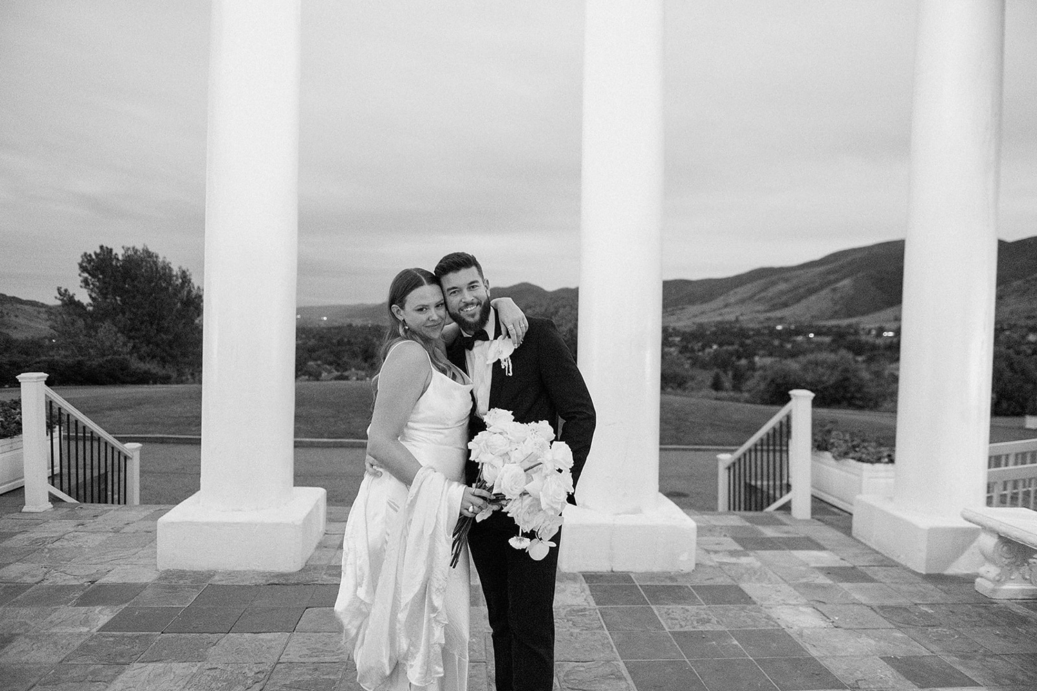 A bride and groom hug each other with pillars in the background at The Manor House