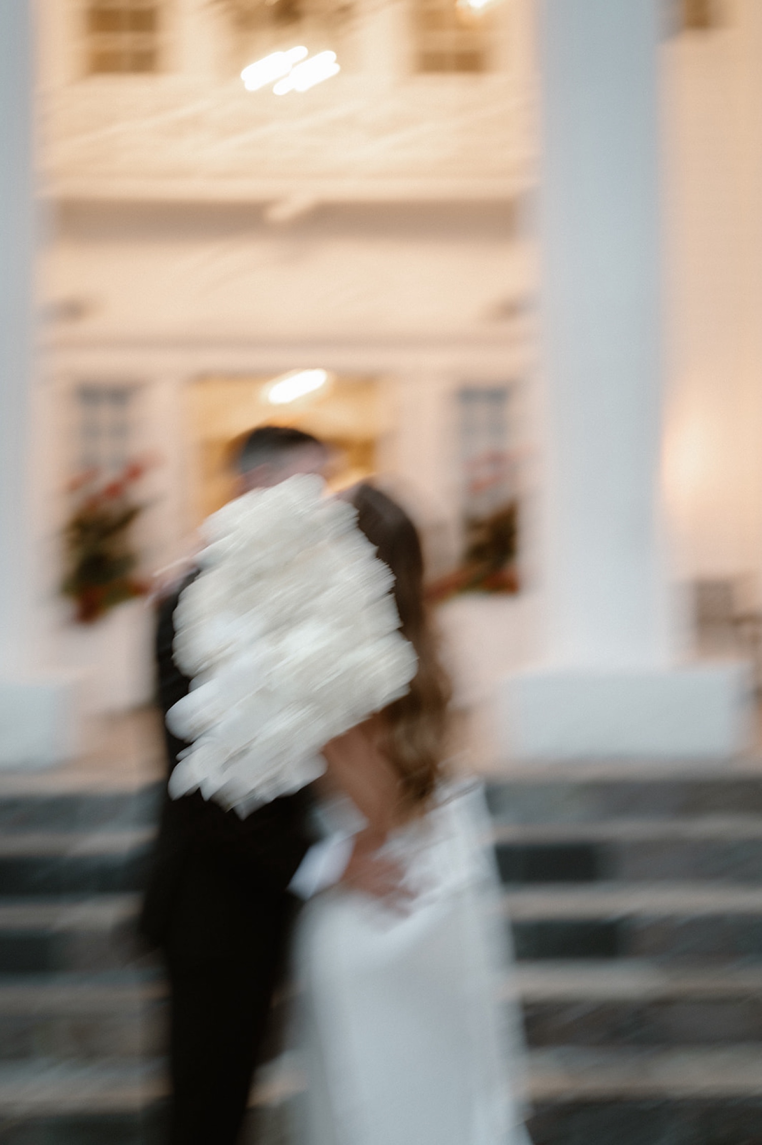 A blurry photo of a bride and groom kissing with flowers in front of their face