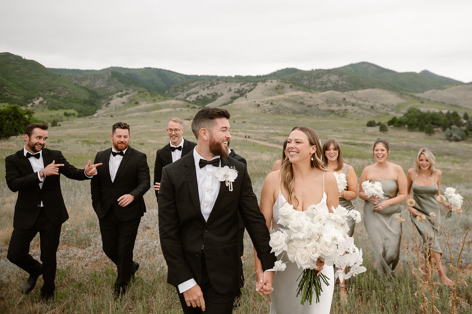 A bride and groom walk towards the camera with their wedding party walking behind them