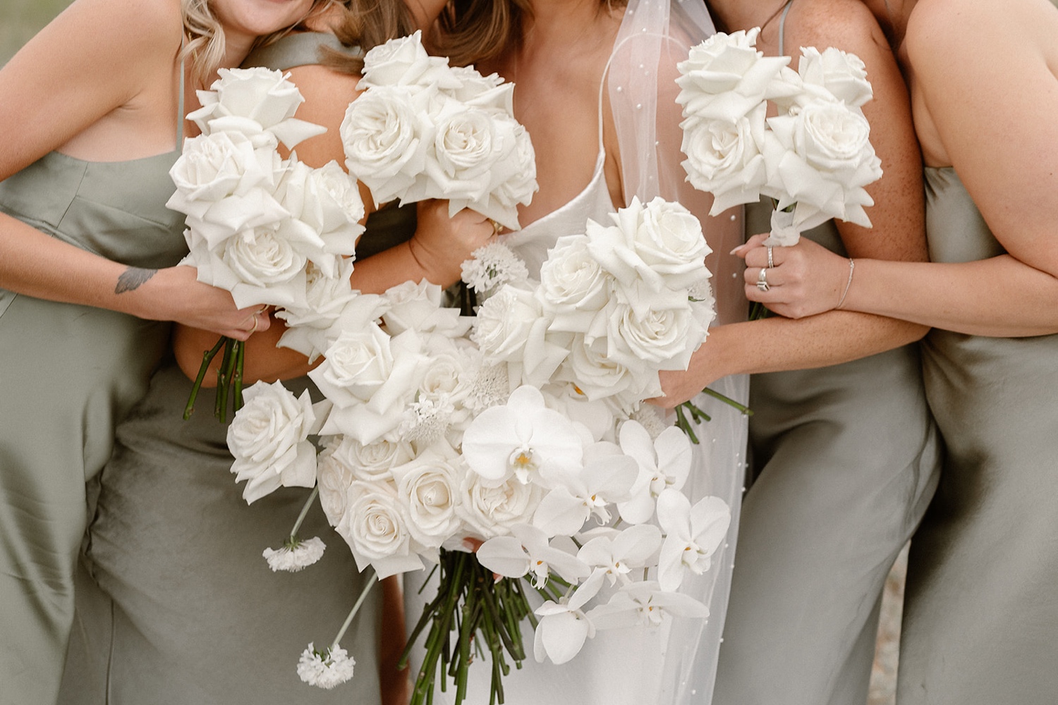 A closeup of a bride and her bridesmaids holding their white wedding bouquets