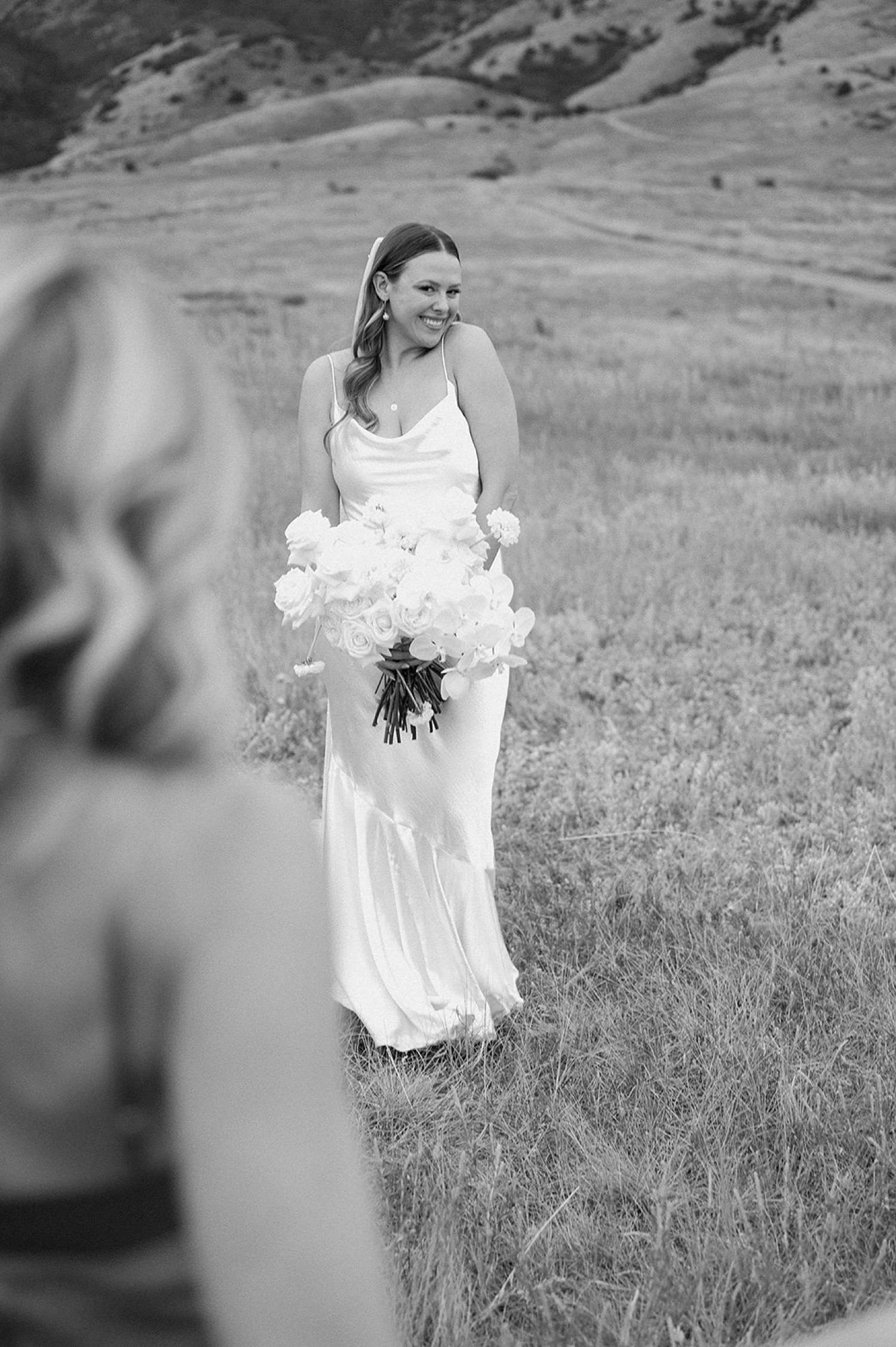 A bride smiles at her bridesmaid