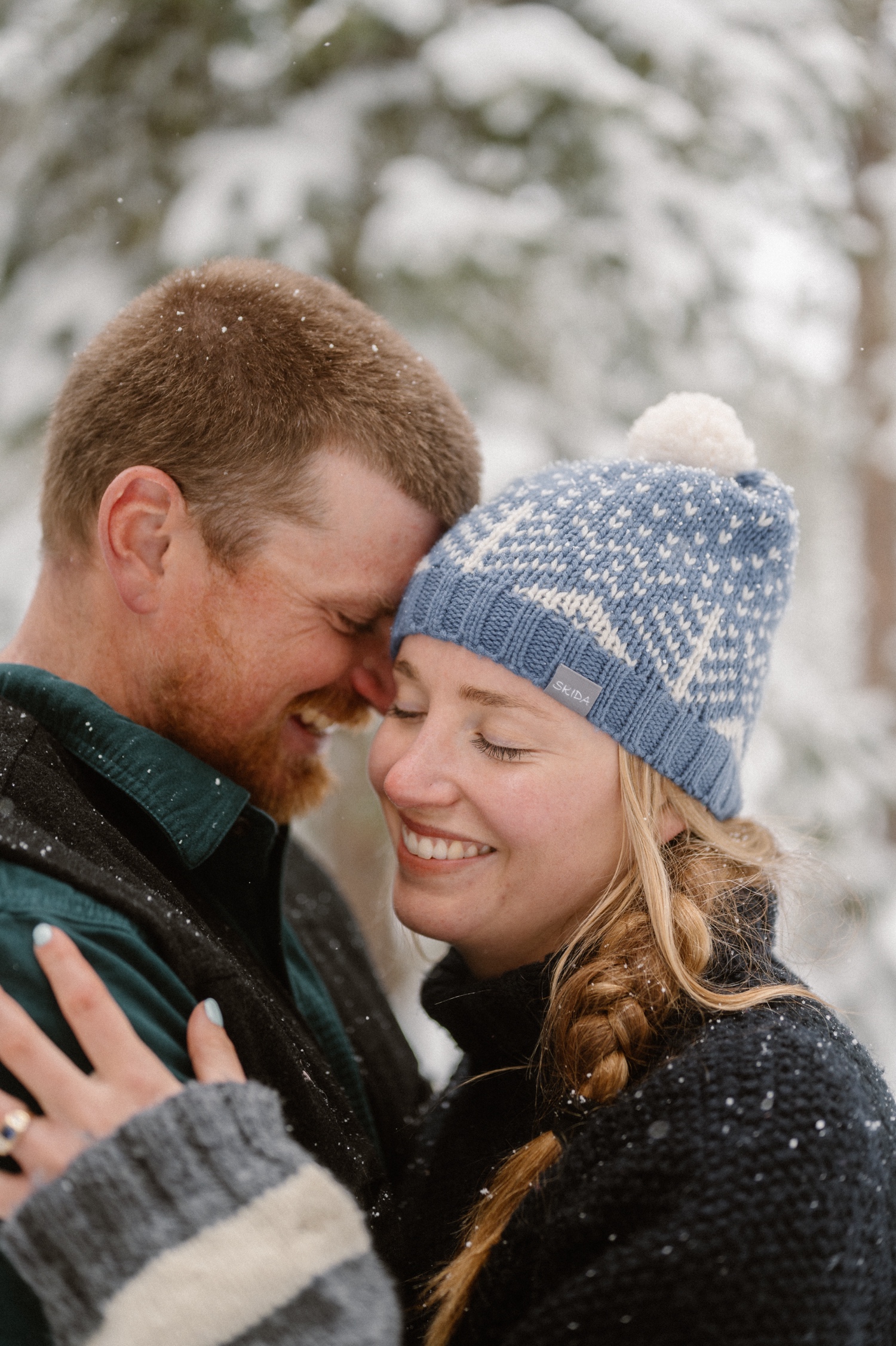 Close-up of the couple's winter engagement outfits with snow-covered trees in the background during their winter engagement photos in Montrose, Colorado.