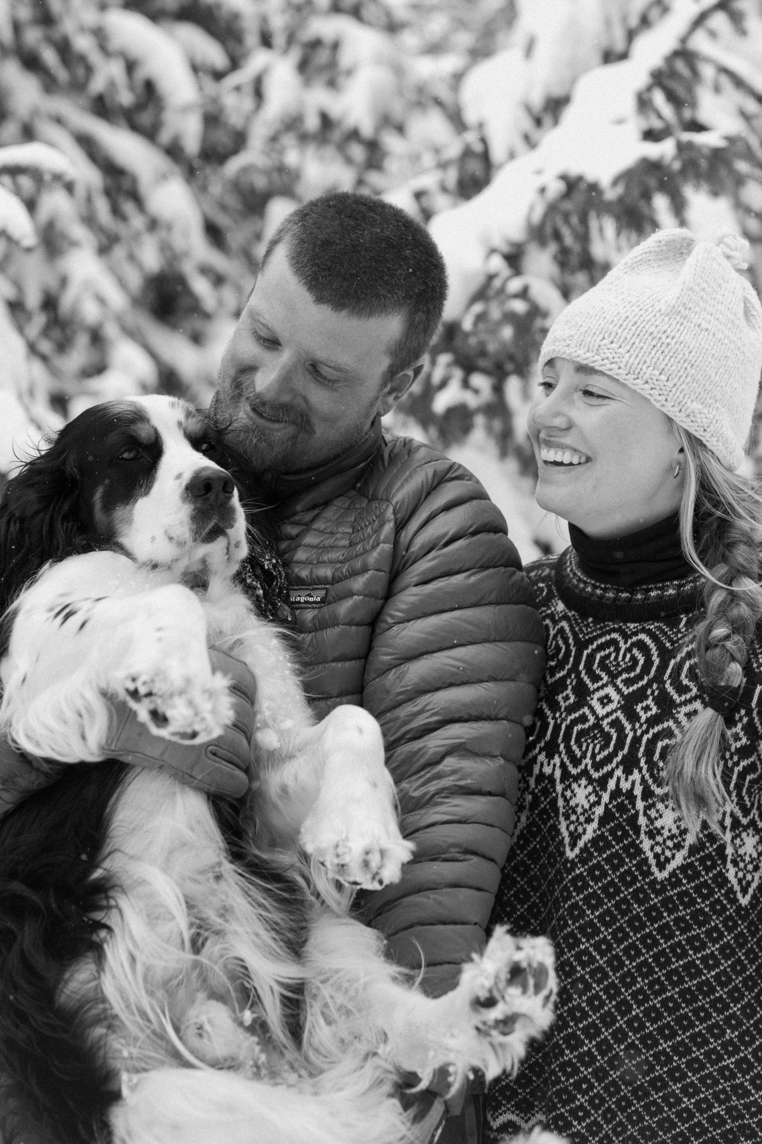 A couple laughing together while bundled up in cozy coats during their winter engagement photo session on cross-country skis in Montrose, Colorado.