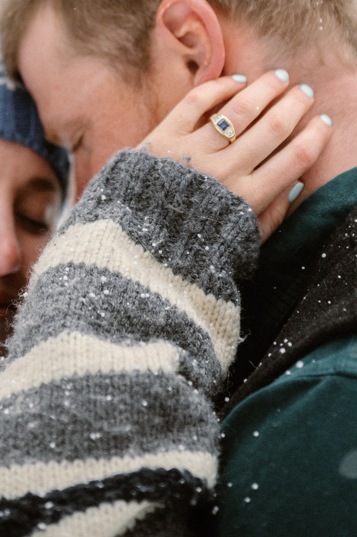 Couple stops for a photo break while cross-country skiing, with snow-covered mountains and winter engagement outfits in the background.