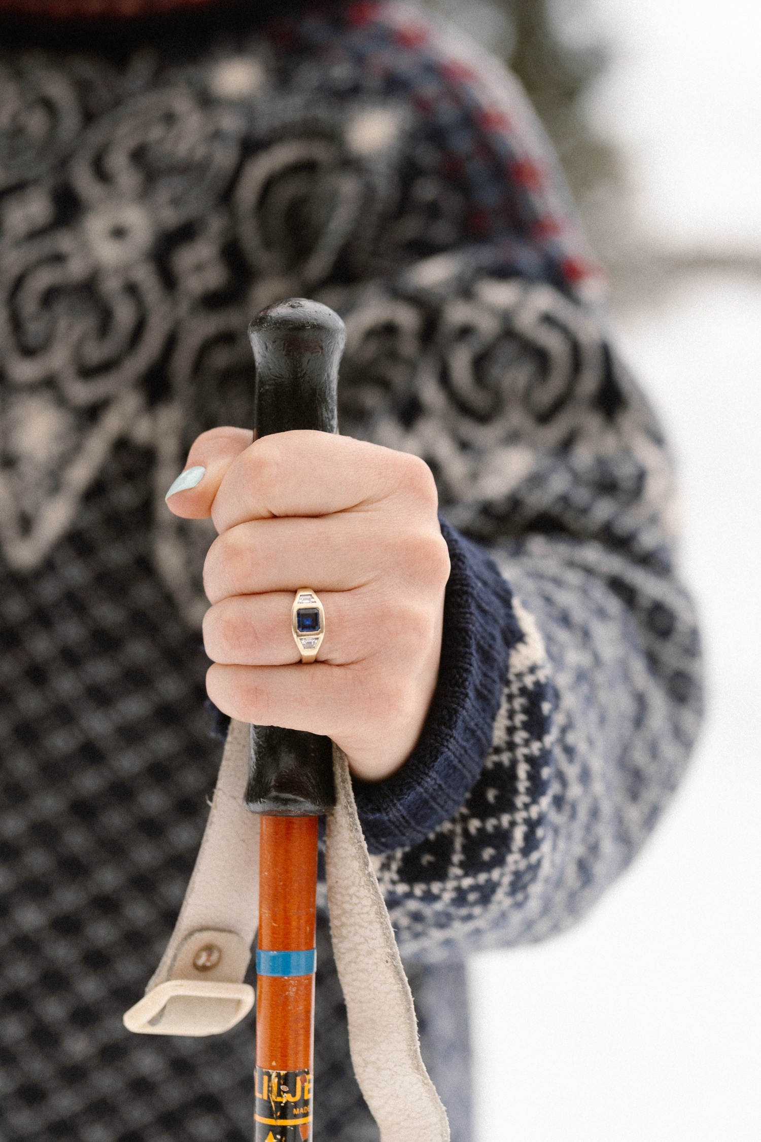 Close-up of the couple's winter engagement outfits and engagement ring with snow-covered trees in the background during their winter engagement photos in Montrose, Colorado.