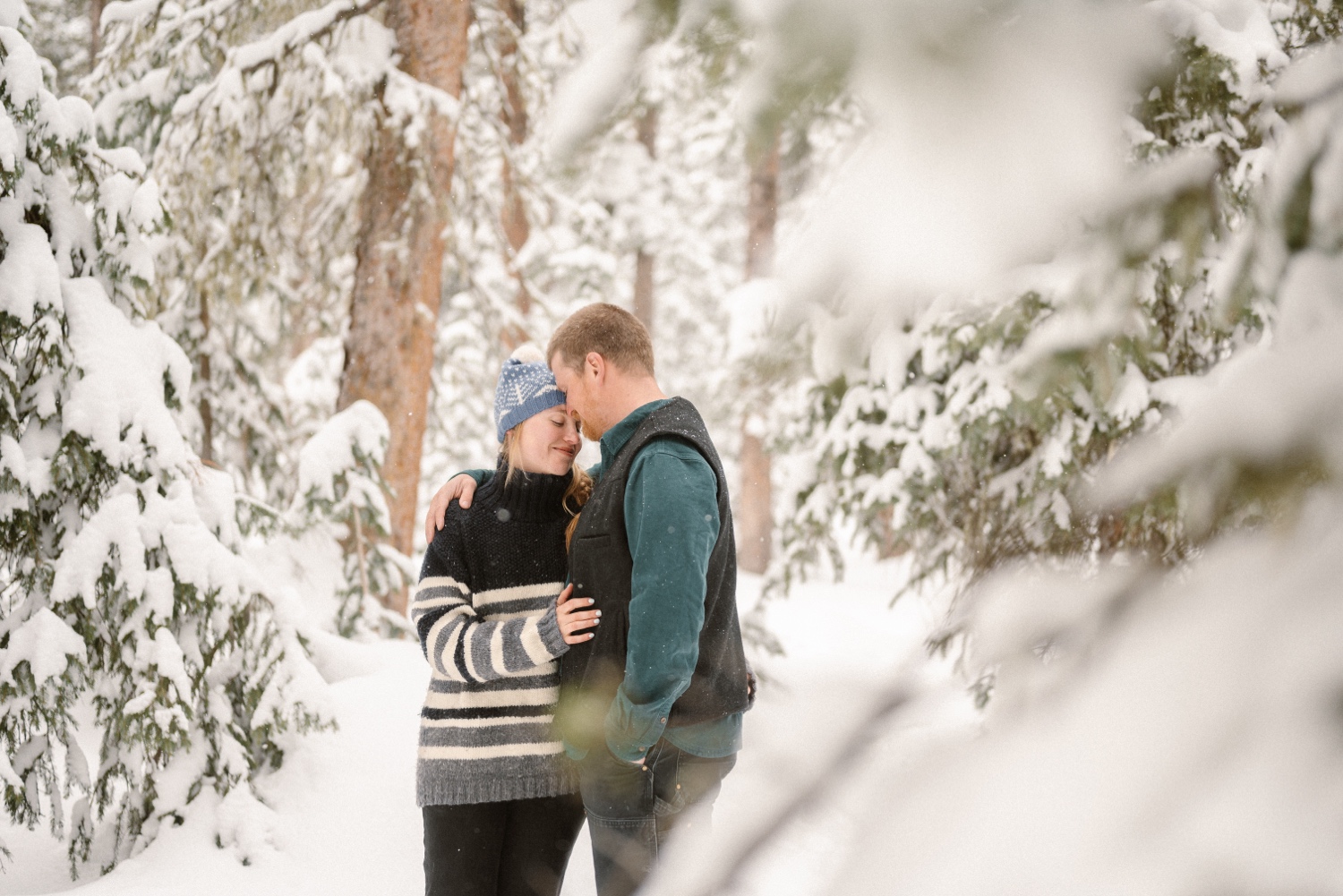 A couple sharing a warm, intimate moment while cross-country skiing in the snow during their winter engagement session in Montrose, Colorado.